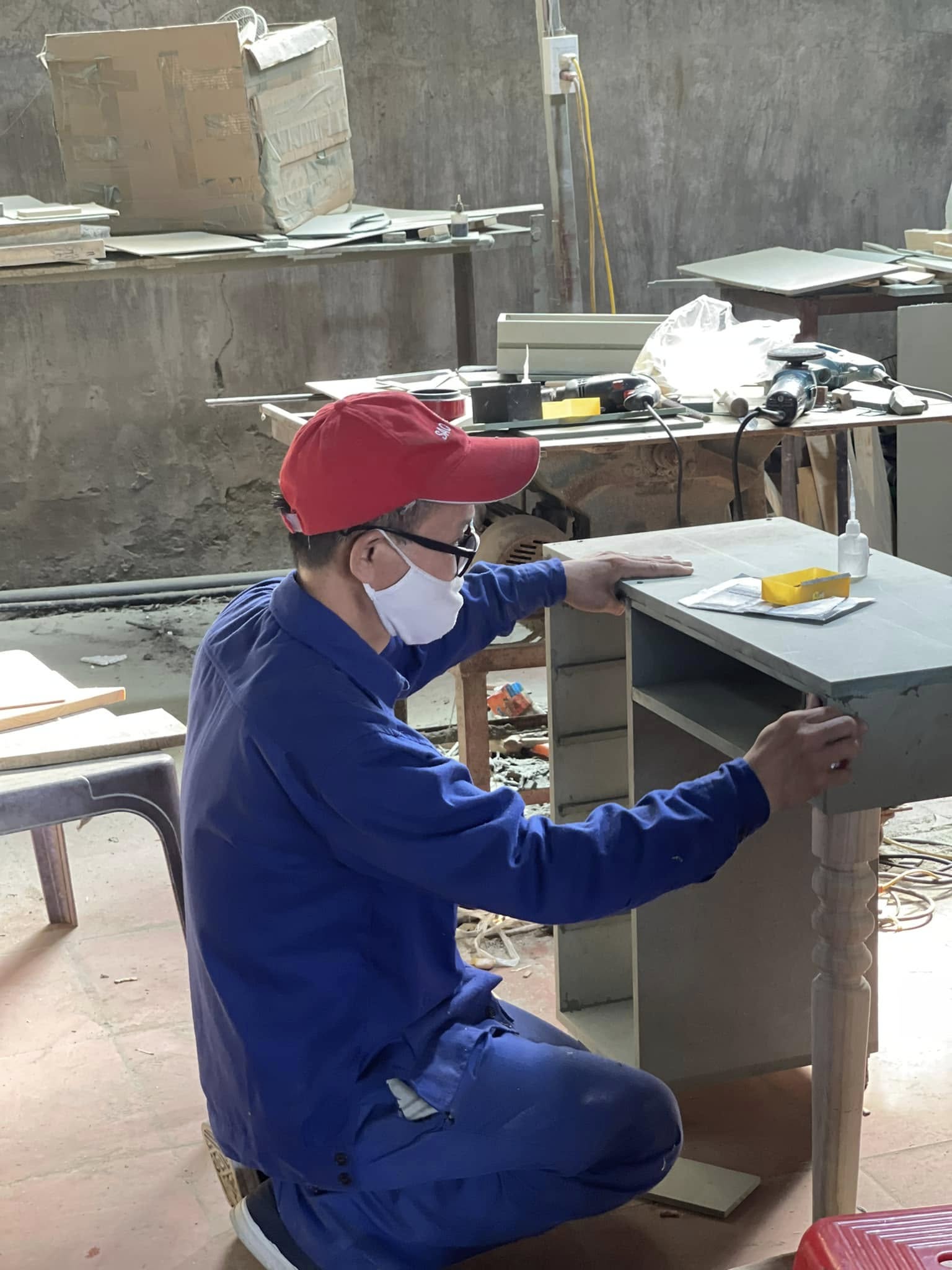 A maker working on a cabinet by hand